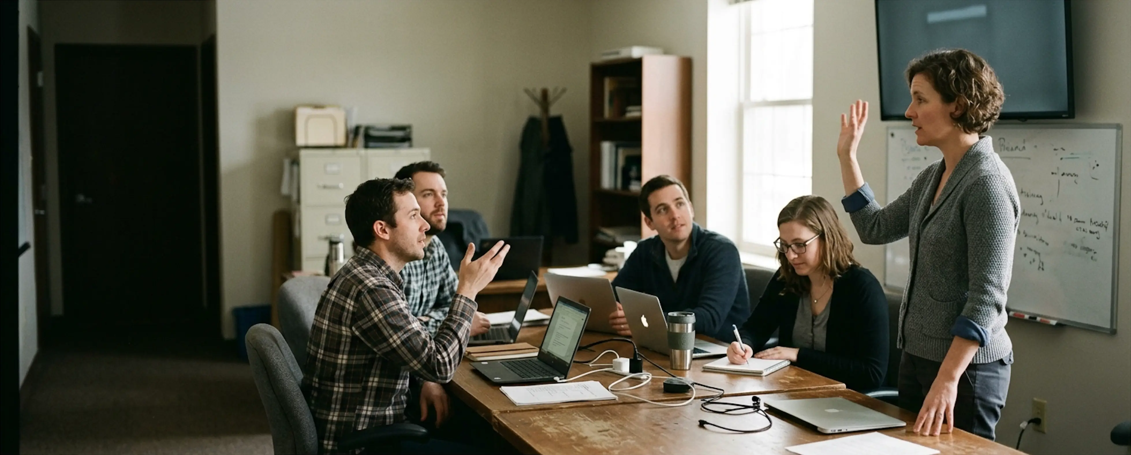 A small group mid working session around a table of laptops